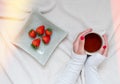 Feminine hands around a coffee, cozy image, strawberries snack. Flat lay