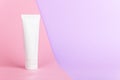 Feminine hygienic product tube on pastel pink and lilac background. Shampoo, hand cream, toothpaste white package side view.