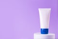 Feminine hygienic product tube on purple background on stand. Shampoo, hand cream, toothpaste white package side view. Skincare, Royalty Free Stock Photo