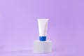 Feminine hygienic product tube on purple background on stand. Shampoo, hand cream, toothpaste white package side view. Skincare, Royalty Free Stock Photo
