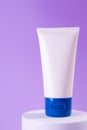 Feminine hygienic product tube on purple background on stand. Shampoo, hand cream, toothpaste white package side view. Skincare, Royalty Free Stock Photo