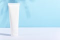 Feminine hygienic product tube on sunny blue background with leaf shadow. Shampoo, hand cream, toothpaste white package side view Royalty Free Stock Photo