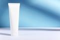 Feminine hygienic product tube on sunny blue background with shadow. Shampoo, hand cream, toothpaste white package side view. Royalty Free Stock Photo