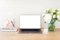 Feminine office desk table with laptop computer with blank white screen, bouquet of flowers, unicorn, stationery and supplies.