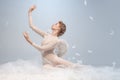Portrait of pretty, slim beautiful young girl, graceful ballerina in image of angel with wings sitting on cloud Royalty Free Stock Photo