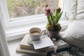 Feminine spring composition. Cup of coffee, books and blank greeting card mockup near window. Vintage Easter styled