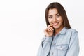 Feminine, tender and beautiful brunette woman in denim jacket, touching lip silly and sensual, smiling beaming from joy