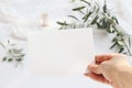 Feminine wedding, birthday greeting card mockup scene with woman`s hand holding blank paper card. Blurred background