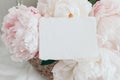 Feminine wedding, birthday mockup scene. Closeup of blank cotton paper card, invitation on pink floral petals. Peony