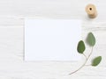 Feminine wedding desktop mock-up with blank paper card, wooden spool and Eucalyptus populus branch on white shabby table Royalty Free Stock Photo