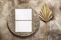 Feminine wedding invitation card. Blank paper cards mockup, dry palm leaf, granite elements and ribbon. Beige grunge background. Royalty Free Stock Photo