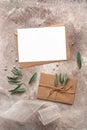 Feminine wedding invitation mockup. Blank card, craft envelope, olive branch and silk ribbon. Beige grunge background. Top view, Royalty Free Stock Photo