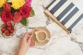 Feminine workplace concept. Freelance workspace in flat lay style with flowers. Woman hand holding cup of coffee. Blogger working. Royalty Free Stock Photo