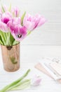 Feminine workspace. Bright and airy desk top with notepad and pink tulips. Vertical Royalty Free Stock Photo