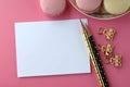 Top view of blank note card, laptop, cell phone and French macarons on pink background. Feminine workspace desktop with copy space Royalty Free Stock Photo