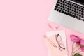 Feminine workspace for distance work with laptop, flowers and stationery. Royalty Free Stock Photo