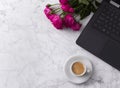 Feminine workspace with laptop computer, bouquet of roses and coffee on a marble table.