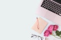 Feminine workspace with laptop, flowers and stationery on a blue background. Royalty Free Stock Photo