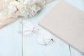 Feminine workspace with paper notebook, glasses, beige cloth on blue wooden background. Flat lay, top view. Beauty blogger Royalty Free Stock Photo