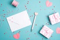 Feminine workspace in Valentines Day style. White paper envelope, pen, hearts, gift boxes on blue background. Flat lay, top view Royalty Free Stock Photo