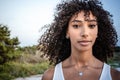 Femininity and beauty in nature: close up portrait of beautiful black Hispanic young woman with curly dark long hair looking