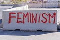 FEMINISM word is written on concrete barrier with paint spray on city street.