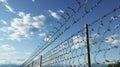 A fence of barbed wire against a blue sky with cirrus clouds. Chains on the Horizon. Generative AI