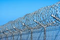 Fence with barbed wire against blue sky with clouds Royalty Free Stock Photo