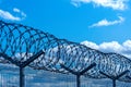 Fence with barbed wire against blue sky with clouds Royalty Free Stock Photo