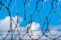 Fence with barbed wire against blue sky with clouds Royalty Free Stock Photo