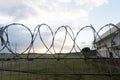 Fence with barbed wire on the border of the object at cloudy morning with sunrise ray of light in the summer, Indonesia Royalty Free Stock Photo