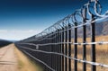 A fence with barbed wire in a field, receding perspective. Fencing at a secret facility Royalty Free Stock Photo