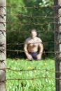 Fence with barbed wire on the foreground and a man on the background