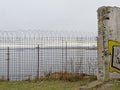 Fence with barbed wire, with sea and coast in the background