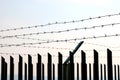 Fence on the border with barbed wire at sunset.