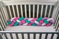 Fence of empty children `s wooden white crib with multicolored braid, fences soft for rib. White in a dot sheet. Cozy bed for the Royalty Free Stock Photo