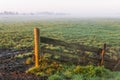 Fence and farmland on a misty morning during sunrise Royalty Free Stock Photo