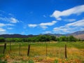 Valley with green grass, trees and mountains in the distance blue sky with whispy clouds Royalty Free Stock Photo