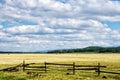 Fence in the green field under blue cloud sky. Beautiful landscape Royalty Free Stock Photo