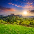 Fence on hillside meadow in mountain at sunset