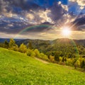 Fence on hillside meadow in mountain at sunset