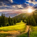 Fence on hillside meadow in mountain at sunset Royalty Free Stock Photo