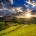 Fence on hillside meadow in mountain at sunset Royalty Free Stock Photo