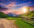 Fence on hillside meadow in mountain at sunset Royalty Free Stock Photo