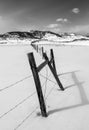 Fence Line Leading Towards Rocky Mountains Through Frigid Snow Covered Field Royalty Free Stock Photo