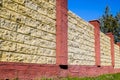 Fence made of bricks and decorative . Yellow fence with red elements. High and beautiful fencing