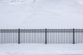 Fence made of cast iron lattices and granite columns in cloudy snowy weather. Royalty Free Stock Photo