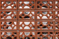 A fence made of decorative molded red bricks in sunlight in winter