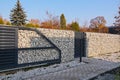 A fence made of gabions. Automatic entrance gate and wicket integrated into the wall made of a gabion