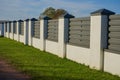 a fence made of a wall and a metal profile, a new fence made of metal profile with white columns has been built, protection of the